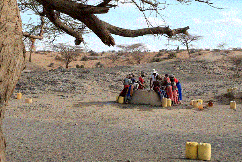 Kvinner står rundt en brønn og heiser opp vann. Landskapet rundt er helt utørket. Foto Noor Kamis
