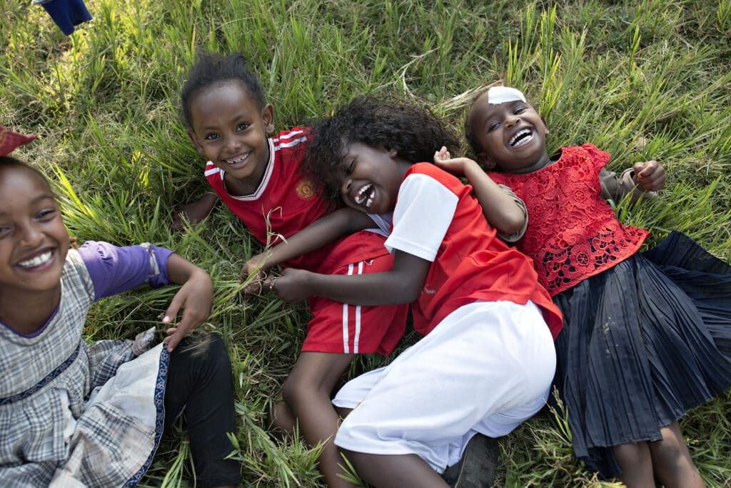 Fire barn i Ethiopia som ler og leker i gresset. Foto: Lars Just