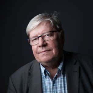 Portrettfoto av Willy Tore Mørk som har på seg mørk grå dressjakke, blårutet skjorte og briller.