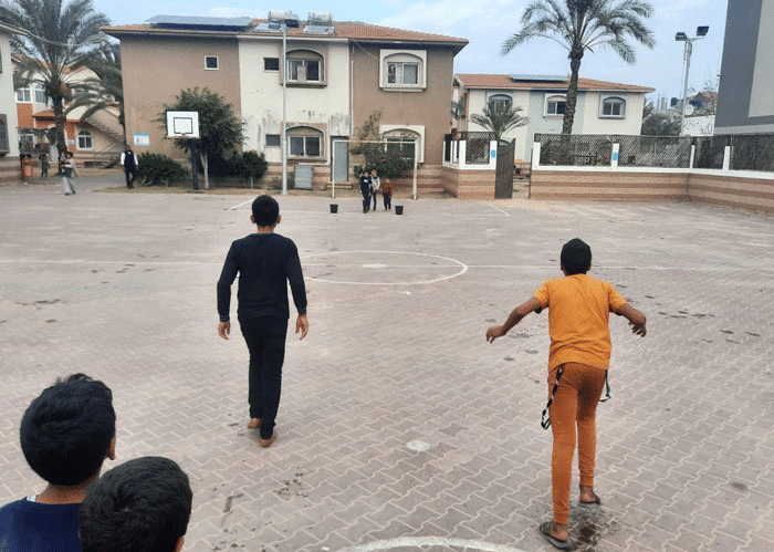 Tre gutter går mot en bygning i SOS-barnebyen i Betlehem. Foto: SOS-barnebyer