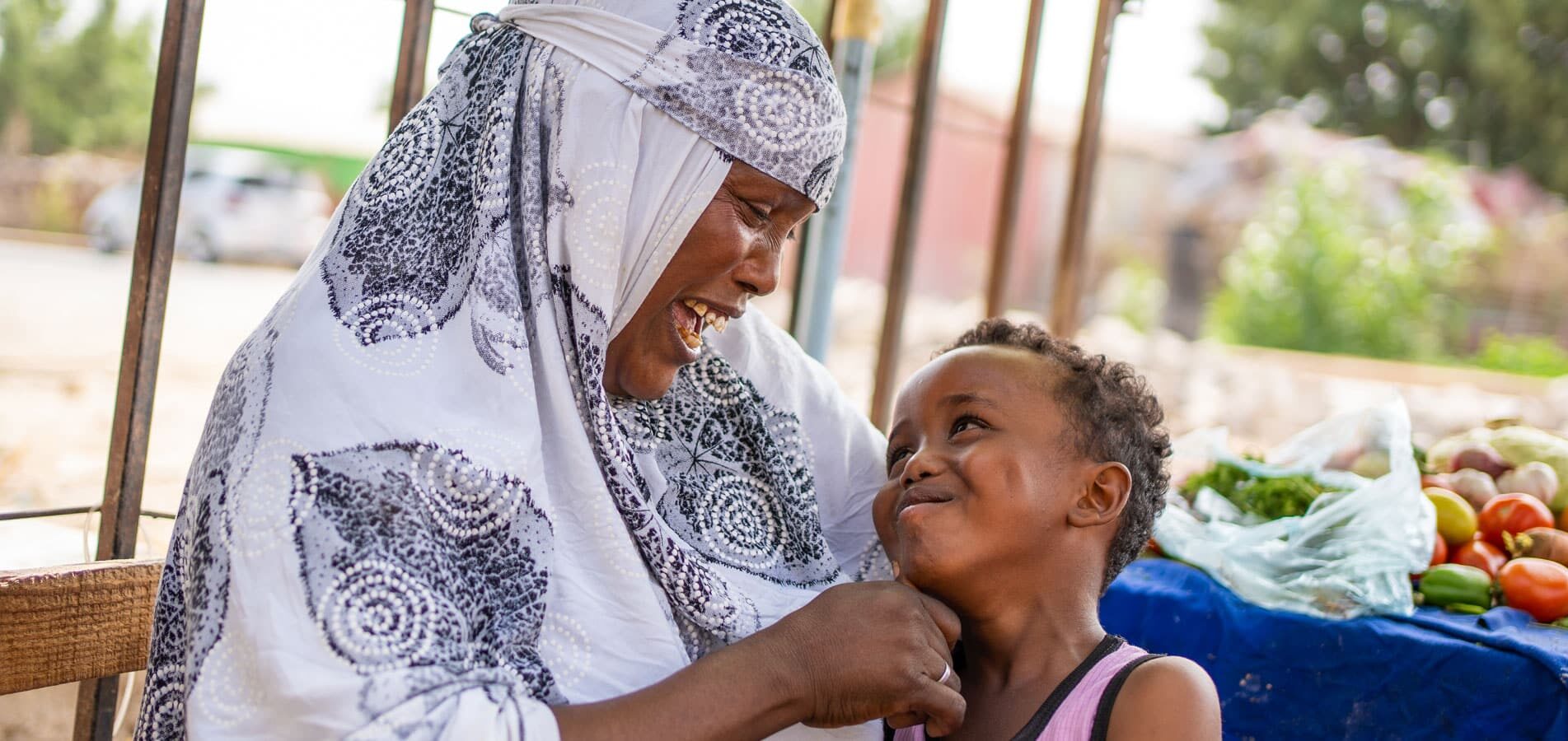 Somaliland: Mor i hvit mønstret hijab har sønnen på fanget. han har rosa singlet og smiler opp til henne. Foto: Lydia Mantler