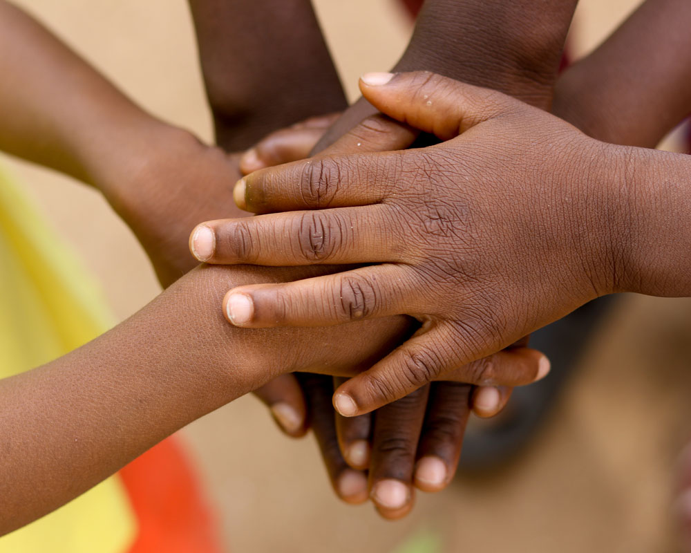 Flere barn holder hendene oppå hverandre. Det er kun hendene og litt av armen som er med på bildet. Foto: Sébastien Taylor