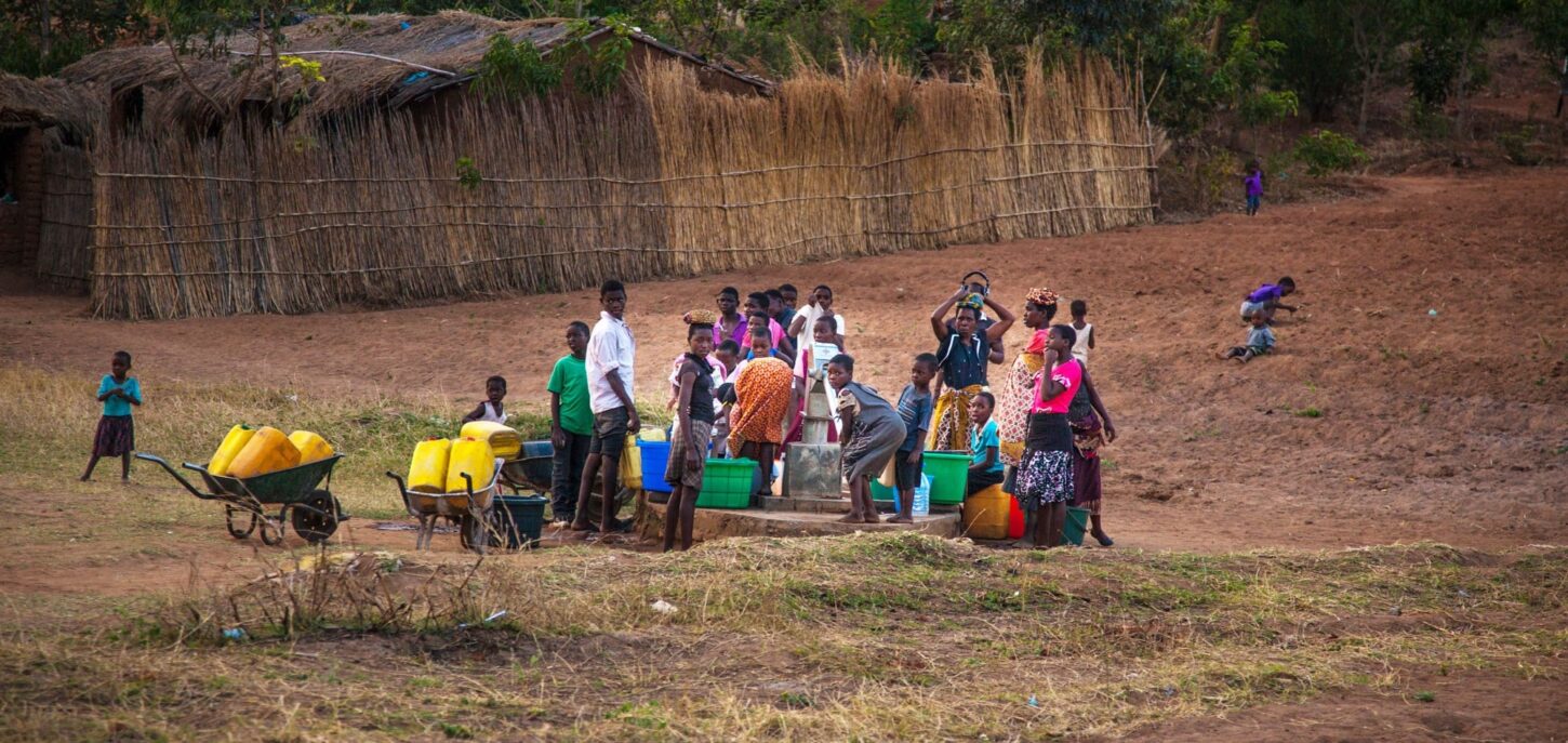 Mange barn står rundt vannposten med kanner og bøtter for å hente vann. Foto: George Kurian