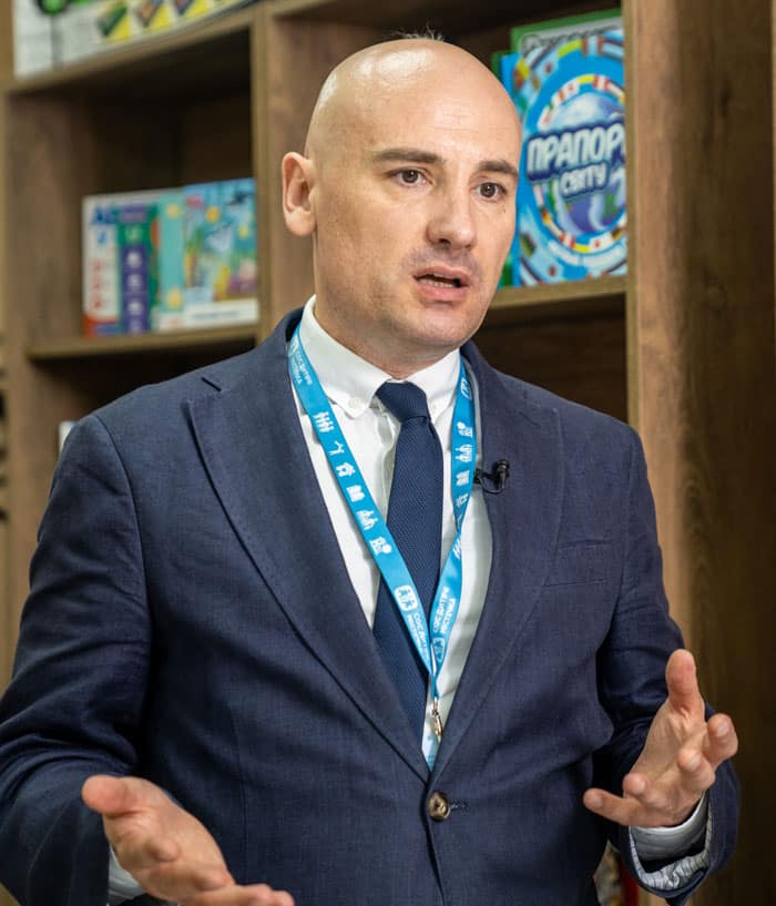 Serhii Lukashov, nasjonaldirektør i SOS-barnebyer Ukraina. han har barbert hode, blå dressk hvit skjorte og slips, og gestikulerer. Foto: Oleksandra Zborovska