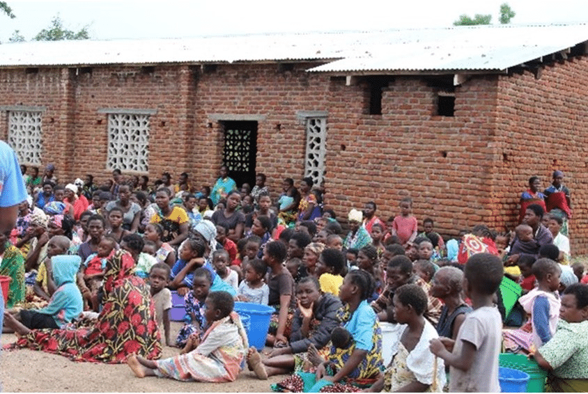 Mange mennesker har søkt tilflukt i skolebygninger, her sitter de utenfor. Foto. SOS-barnebyer Malawi