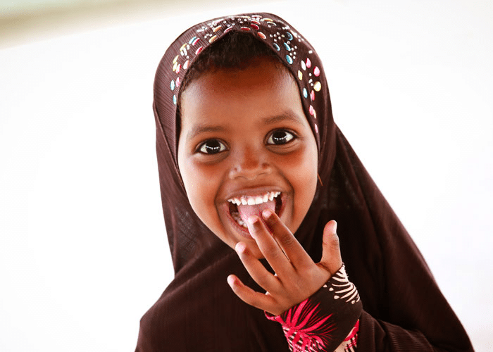 Jente på fem år med brun hijab, smiler strålende. Foto: On Screen Productions Kevin Ouma