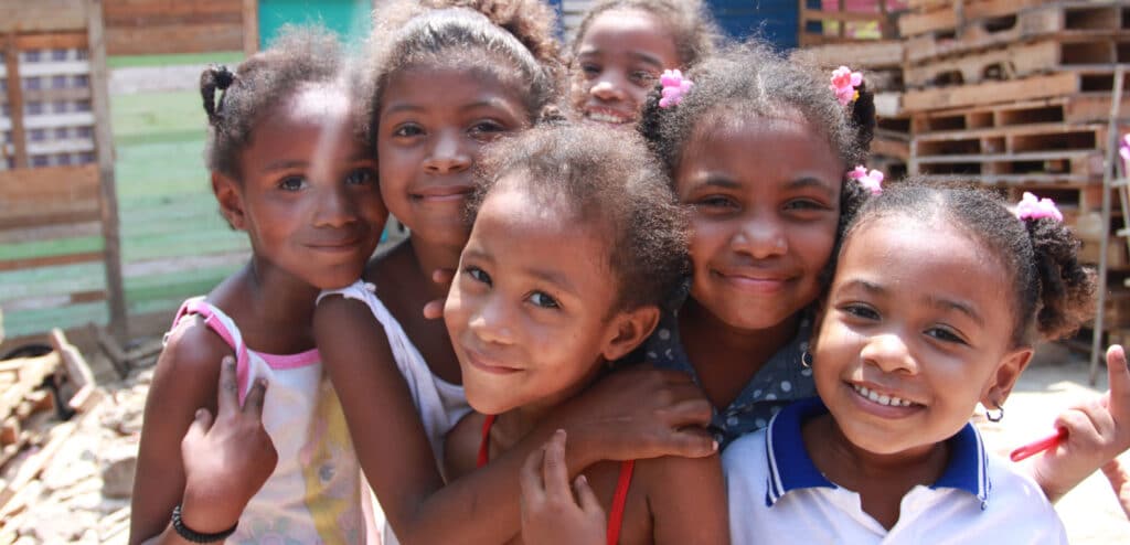 Seks jenter fra Colombia står tett sammen. Alle har krøllete hår med fine spenner og strikker. Foto: Foto: Giti Carli Moen