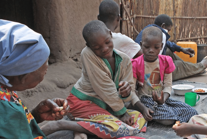 En mor og barna hennes sitter på bakken og spiser middag. Foto: Bjørn Owe Holmberg
