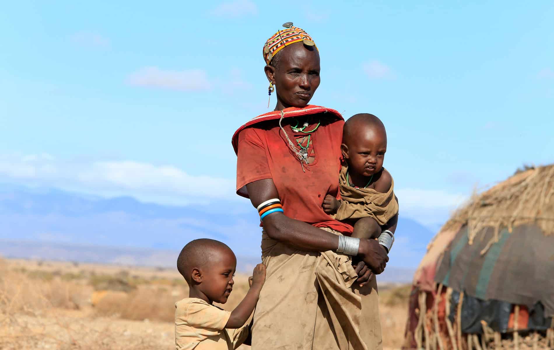 En kvinne og to av barna hennes. Hun bærer det minste barnet på armen og en liten gutt har et godt tak i skjørtet hennes. Foto: Noor Kamis