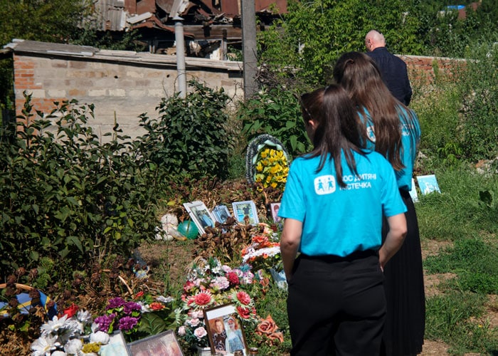 Ukraina: SOS-barnebyers medarbeidere står ute ved et sted der det er bilder av drepte i krigen, det også er lagt ned mange blomster. Foto Katerina Ilievska