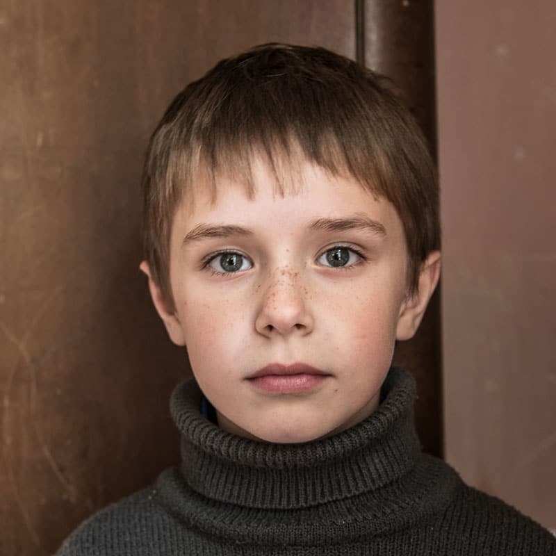 Gutt fra Ukraina med mørkeblondt kort hår og brun høyhalset genser. Bak ham er det en brun vegg. Foto: Katerina Ilievska
