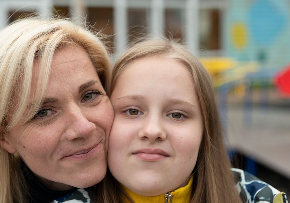 Moren, med lyst halvlangt hår, gir Sofiya, som har blond langt hår, en klem. Foto: Katerina Ilievska