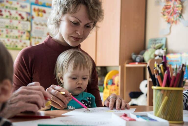 Et barn sitter på fanget til mor og tegner. Foto: Katerina Ilievska