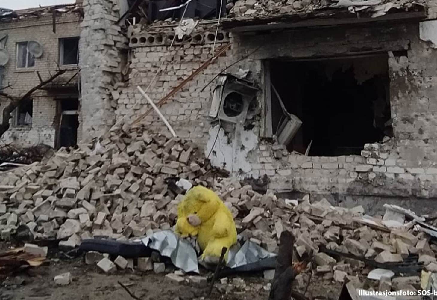 Et hus i ruiner. I forgrunnen ligger en kosebamse. Illustrasjonsfoto SOS-barnebyer Ukraina