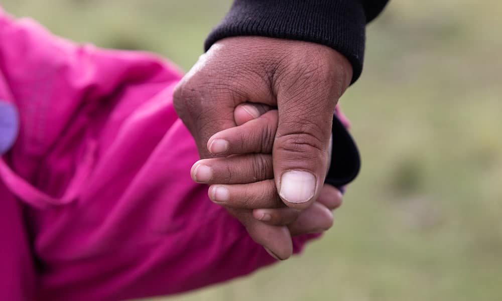 Peru: Bilde av to hender, en far holder datterens hånd, hun har rosa jakke. foto Pierre Devé