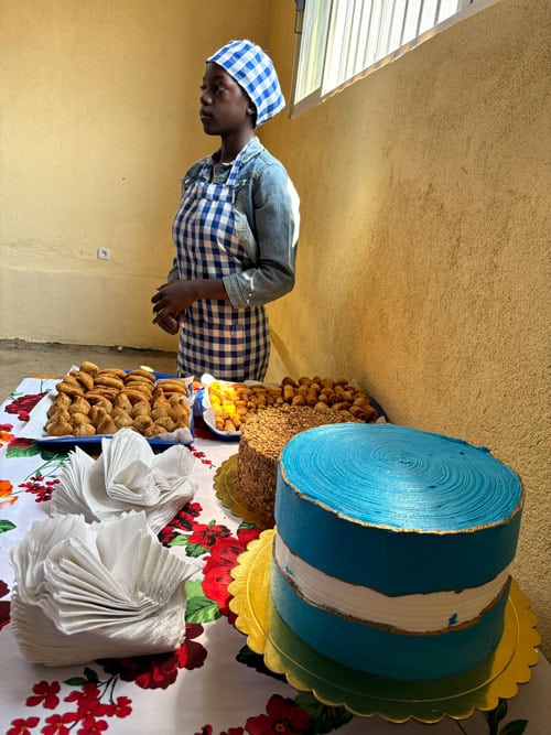 Opplæring i baking og matlaging: Her presenterer Anna Rebecca forskjellige kaker de har bakt, blant annet «sigarkake». Hun har på seg rutet tørkle på hodet og rutet forkle. Foto: Sigurd Skjefstad