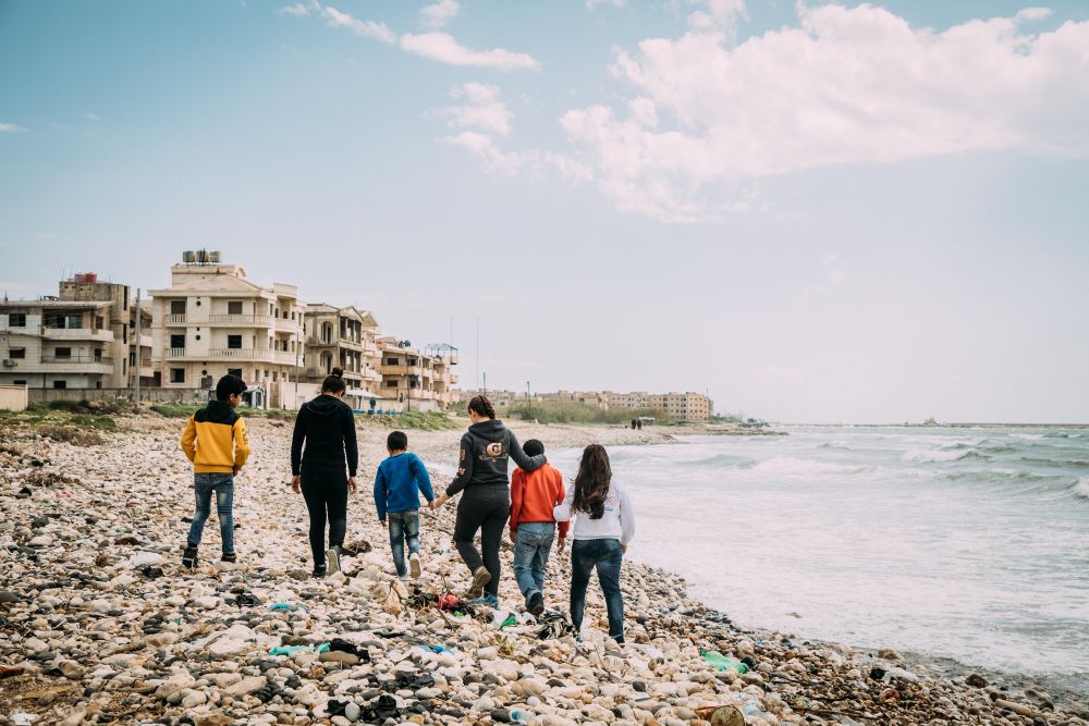 Barn fotografert bakfra går på en strand i Syria