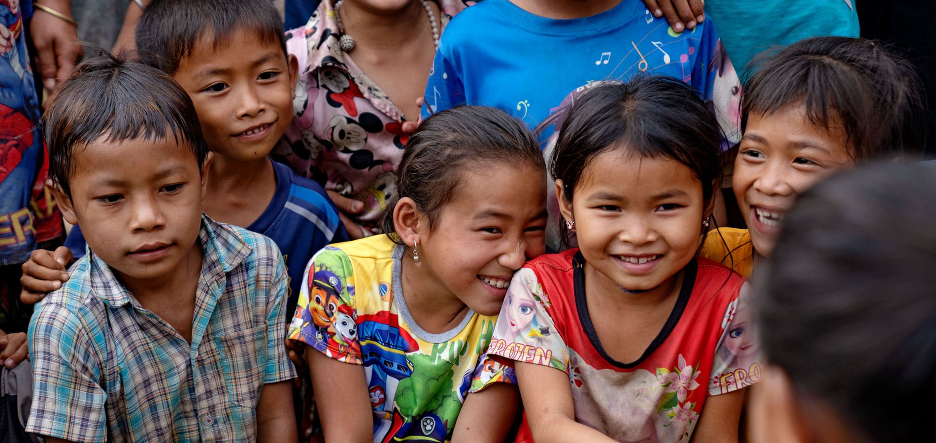 Mange barn fra Laos står tett sammen og smiler. Foto Agnete Schlichtkrull