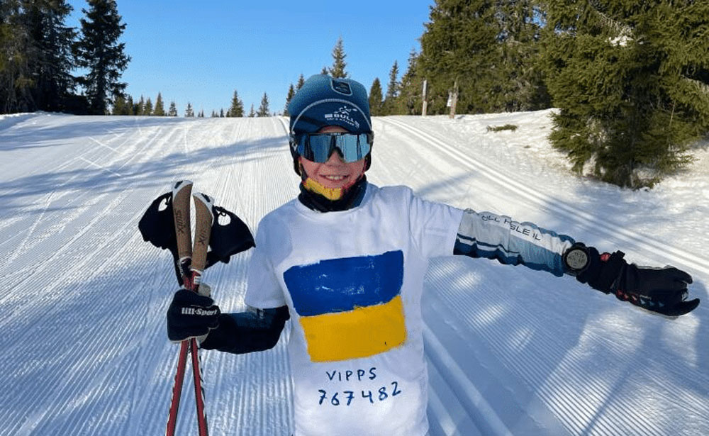 Magnus Semb (10 år) i løypene på Sjusjøen. han har hvit t-skjorte utenpå skidressen der han har malt de ukrainske fargene og vippsnr. 767482. Foto: Privat